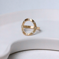 Gold open circle Sarin ring with 8 diamonds on a white ceramic surface