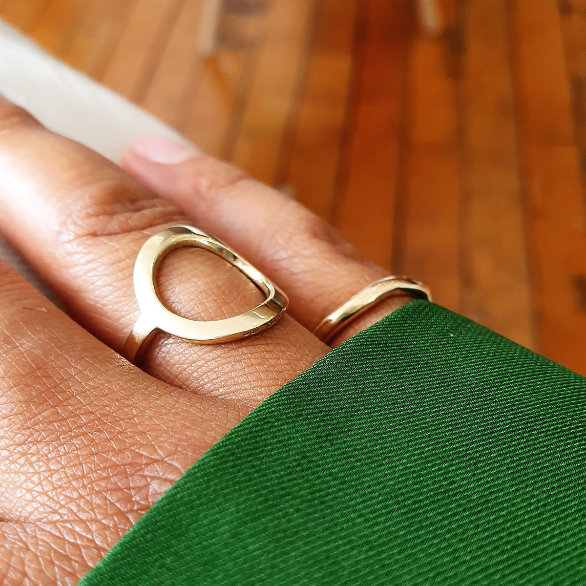 A gold open circle ring is displayed on a person's finger